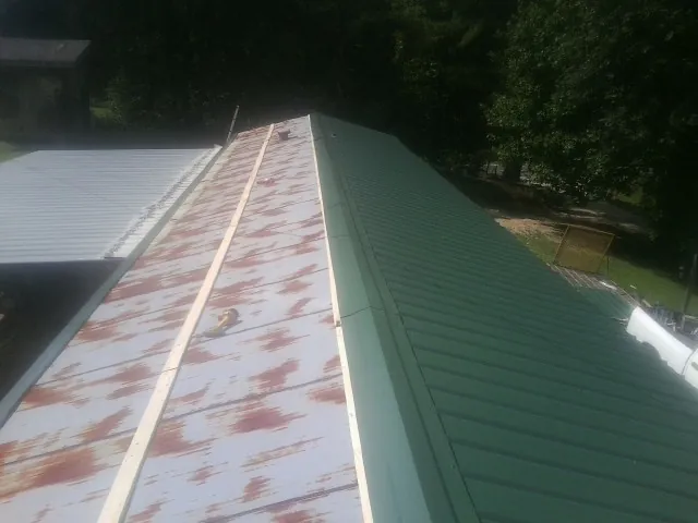 Old rusted panels beside newly installed green metal roofing — Wind Damage Roof Repair by Roofing Brothers in Fort Howard