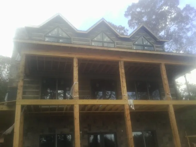Dormers and porch framing on a large log home under construction — Roof Coating work by our crew in Fort Howard