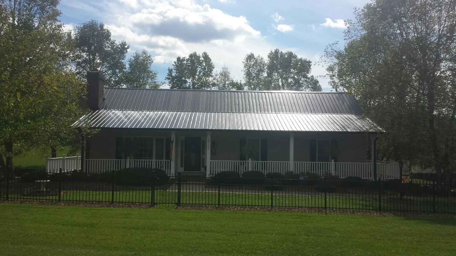 Gray metal roof on a brick ranch with a full width front porch — Gutter Guard Installation work by our crew in Fort Howard