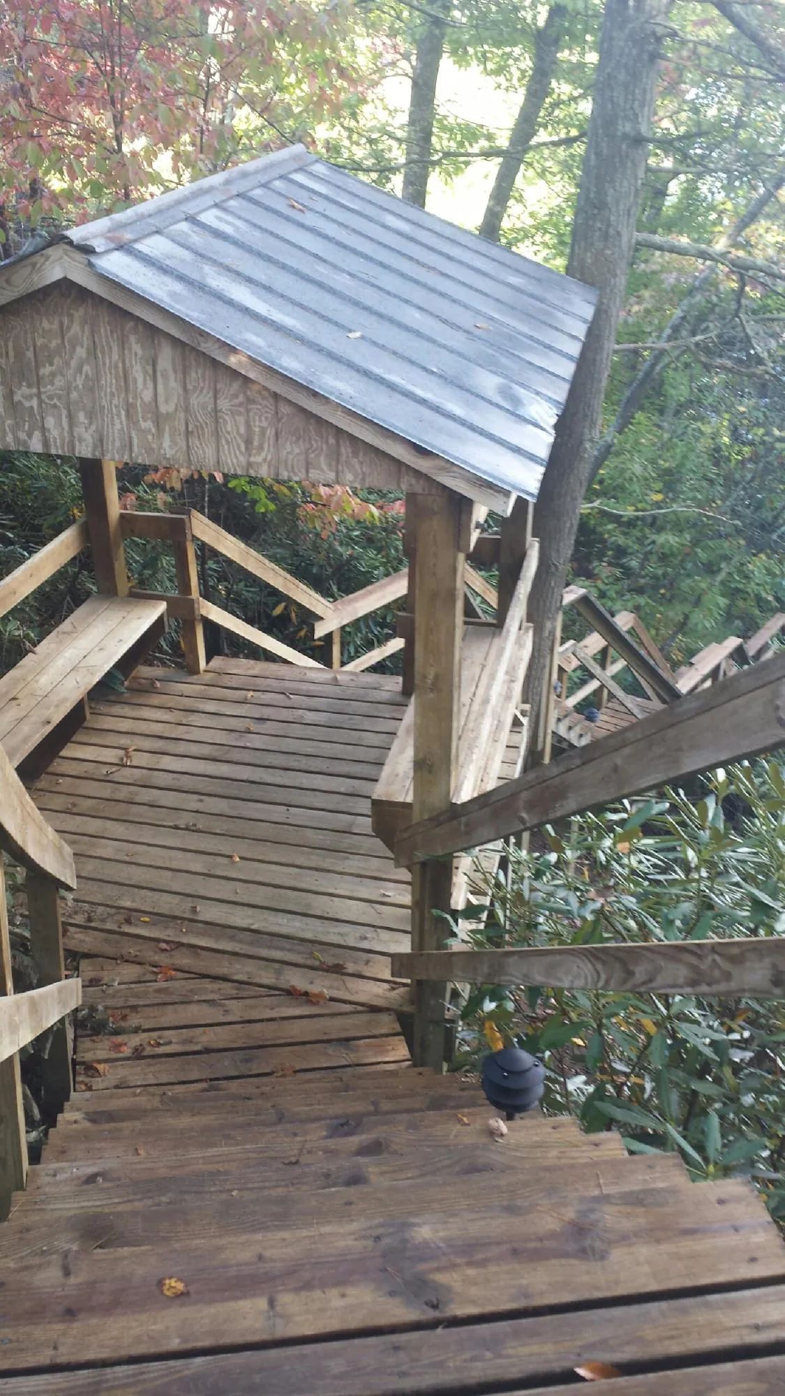 Metal roofed shelter over wooden steps on a wooded walkway — Skylight Repair & Installation work by our crew in Fort Howard