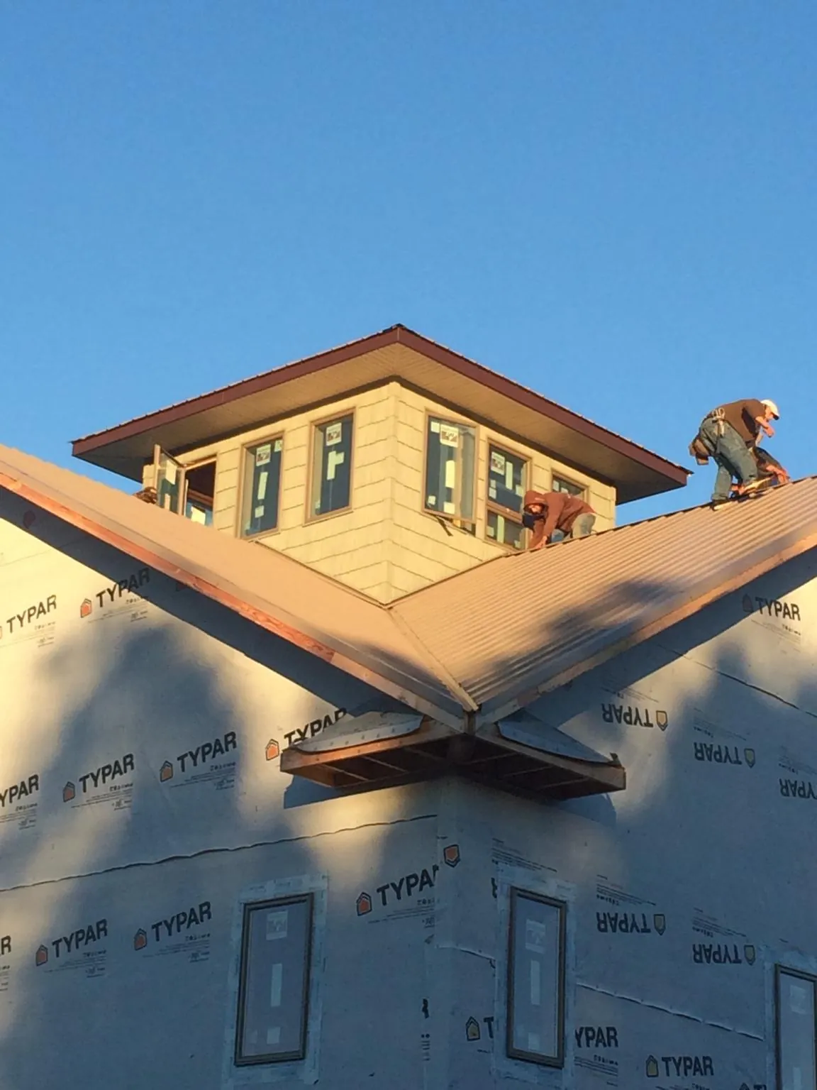 Roofers working around a rooftop cupola on a new metal roof at sunset — Roof Waterproofing in Fort Howard by Roofing Brothers
